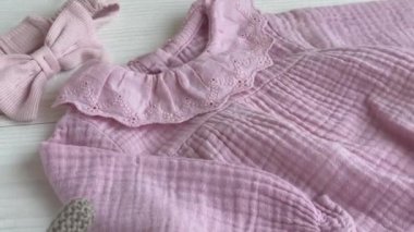 Oyuncak köpek, çorap ve saç bandıyla pembe bir beden. Yazın beyaz ahşap arka planda bebek kıyafetleri ve aksesuarlar. Yeni doğan moda. Düz yatış, üst görünüm