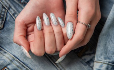 Kotun arka planında mavi tırnak desenli bir kadın eli. Mavi oje manikür.. 