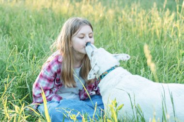 Doğada köpeği olan bir çocuk, yeşil çimlerde köpekle oynayan bir kız.