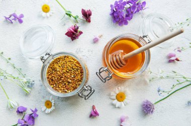 Çiğ organik arı poleni, kavanozlarda bal ve yabani çiçekler..