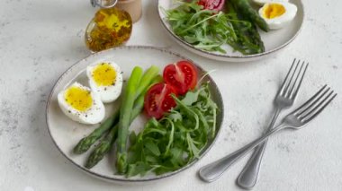 Parlak bir günde haşlanmış yumurta, kuşkonmaz ve domatesli taze bahar salatası.