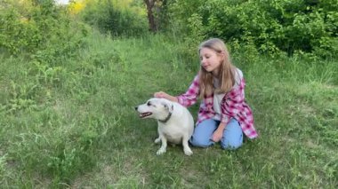 Doğada köpeği olan bir çocuk, yeşil çimlerde köpekle oynayan bir kız.