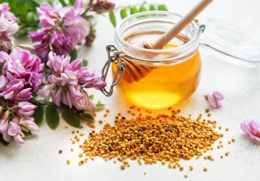 Çiğ organik arı poleni ve kavanozlarda bal ve akasya çiçekleri. 
