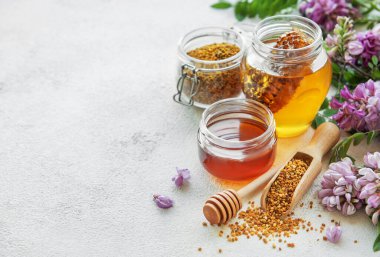 Çiğ organik arı poleni ve kavanozlarda bal ve akasya çiçekleri. 