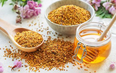 Çiğ organik arı poleni ve kavanozlarda bal ve akasya çiçekleri.