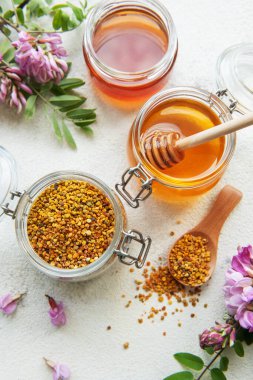 Çiğ organik arı poleni ve kavanozlarda bal ve akasya çiçekleri. 