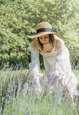 Genç ve güzel bir kadın lavanta çiçeği topluyor.