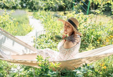 Genç bir kadın arka tarafta bir hamakta dinleniyor.