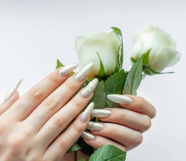 Beyaz bir zemin üzerinde kadın elleri Güzel bir inci manikür ve beyaz gül