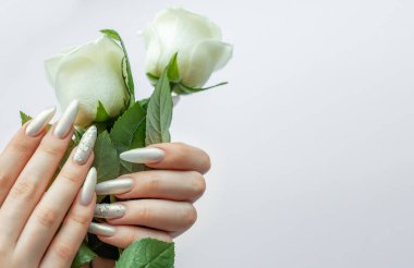 Beyaz bir zemin üzerinde kadın elleri Güzel bir inci manikür ve beyaz gül