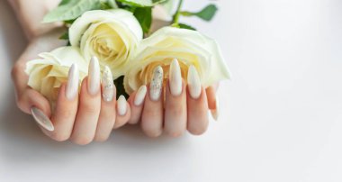 Güzel inci manikürlü ve beyaz güllü kadın elleri