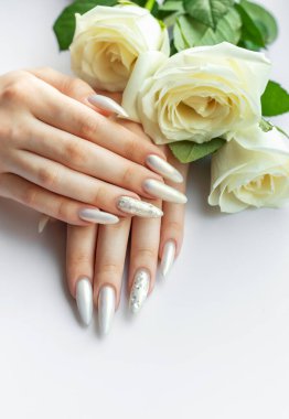 Güzel inci manikürlü ve beyaz güllü kadın elleri