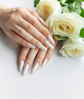 Güzel inci manikürlü ve beyaz güllü kadın elleri