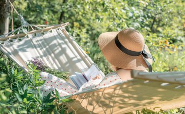 Genç bir kadın arka tarafta bir hamakta dinleniyor.