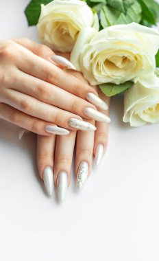 Güzel inci manikürlü ve beyaz güllü kadın elleri