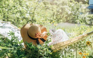 Arka bahçedeki hamakta dinlenen genç bir kadın.
