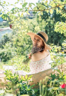 Genç bir kadın arka tarafta bir hamakta dinleniyor.