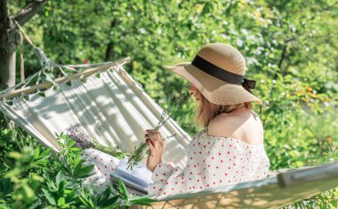 Arka bahçedeki hamakta dinlenen genç bir kadın.