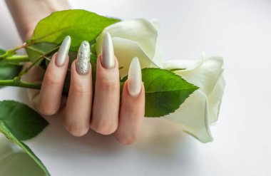 Güzel inci manikürlü ve beyaz güllü kadın elleri