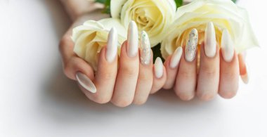 Güzel inci manikürlü ve beyaz güllü kadın elleri