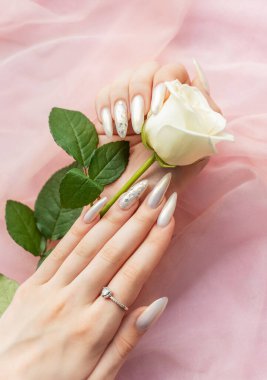 Güzel inci manikürlü ve beyaz güllü kadın elleri