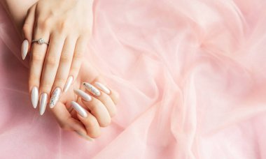 Pembe arka planda güzel inci manikürlü kadın elleri.