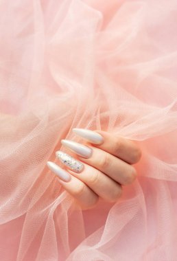 Pembe arka planda güzel inci manikürlü kadın elleri.