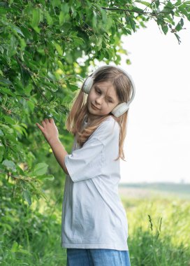 Kulaklıklı bir çocuk parkta müzik dinliyor ve dans ediyor..