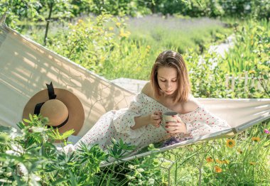 Arka bahçedeki hamakta dinlenen genç bir kadın.