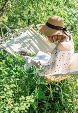 Arka bahçedeki hamakta dinlenen genç bir kadın.