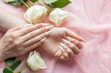 Güzel inci manikürlü ve beyaz güllü kadın elleri