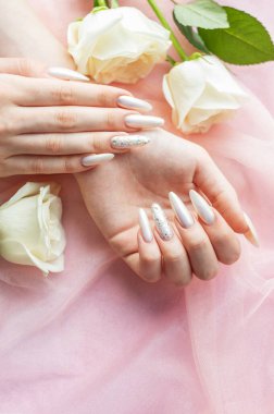 Güzel inci manikürlü ve beyaz güllü kadın elleri