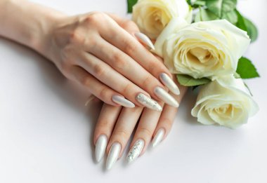 Güzel inci manikürlü ve beyaz güllü kadın elleri