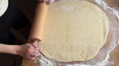 Pişiren genç bir kadın. Tarçınlı çörekler için hamur hazırlama süreci