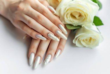 Güzel inci manikürlü ve beyaz güllü kadın elleri