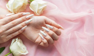 Güzel inci manikürlü ve beyaz güllü kadın elleri