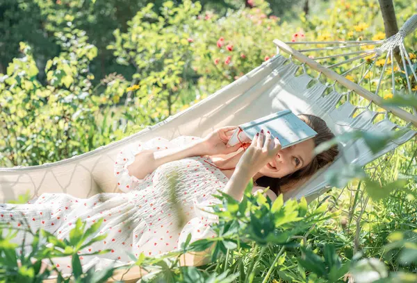 Genç bir kadın arka tarafta bir hamakta dinleniyor.