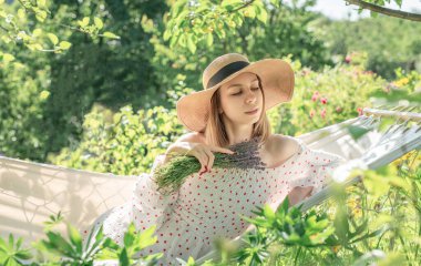 Genç bir kadın arka tarafta bir hamakta dinleniyor.