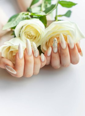 Beyaz bir zemin üzerinde kadın elleri Güzel bir inci manikür ve beyaz gül