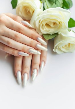 Güzel inci manikürlü ve beyaz güllü kadın elleri