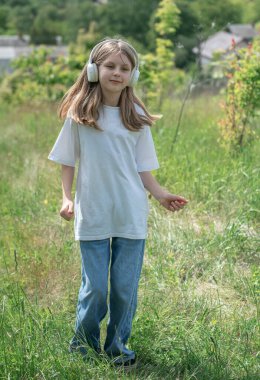 Kulaklıklı bir çocuk parkta müzik dinliyor ve dans ediyor..