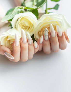 Güzel inci manikürlü ve beyaz güllü kadın elleri