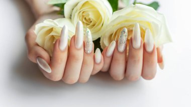 Güzel inci manikürlü ve beyaz güllü kadın elleri