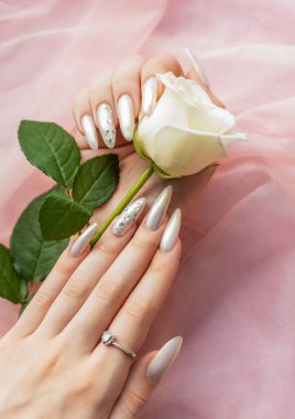 Güzel inci manikürlü ve beyaz güllü kadın elleri