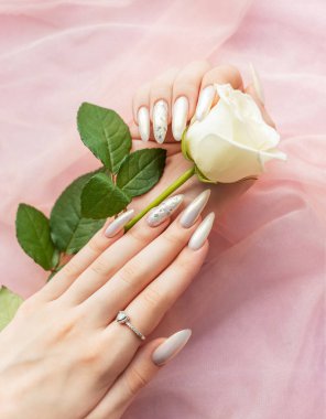 Güzel inci manikürlü ve beyaz güllü kadın elleri
