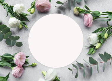 Yaratıcı bir düzen, davetiyeler veya dekoratif amaçlar için ideal gri bir yüzey üzerinde boş bir çemberin etrafına yerleştirilmiş pembe ve beyaz çiçeklere sahiptir..