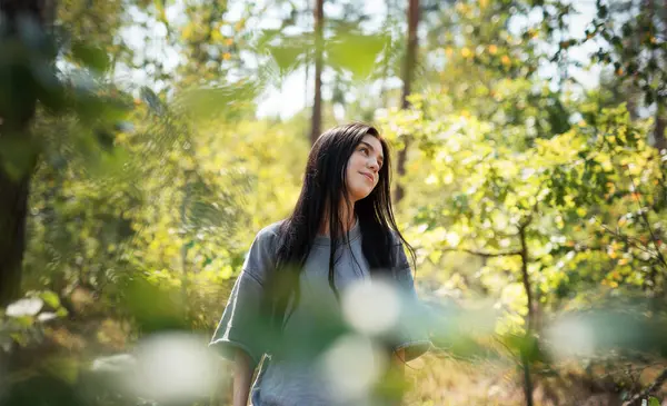 stock image A young girl who breathes fresh air and relieves stress in the forest. Dreamy peaceful relaxed girl breathing the fresh air of nature.