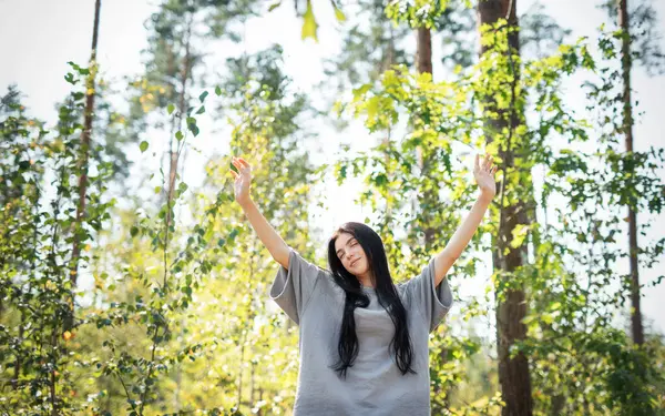 stock image A young girl who breathes fresh air and relieves stress in the forest. Dreamy peaceful relaxed girl breathing the fresh air of nature.