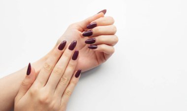 Two hands showcase a stylish deep burgundy nail design on a stark white surface, highlighting the details of a recent manicure session. clipart