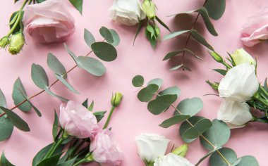 Taze yeşilliklerle çevrili pembe ve beyaz tonlarında pastel güllerden oluşan bir kolleksiyon yumuşak pembe bir arka plana karşı sakin ve zarif bir görüntü oluşturur..